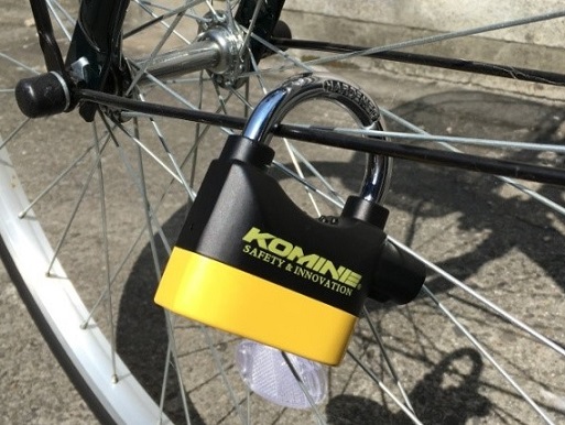 自転車の前輪に黄色のアラーム装置を取り付ける。