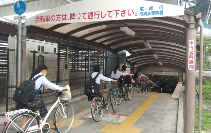 自転車から降りて押して歩く学生たち
