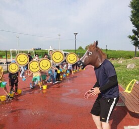 打ち水をかけられる馬マスクの職員