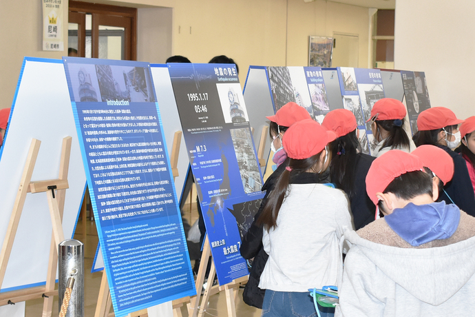 写真、地震に関するパネルを見る小学生