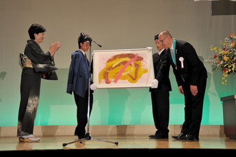 記念式典でリトグラフ・芬（ふん）授与の様子